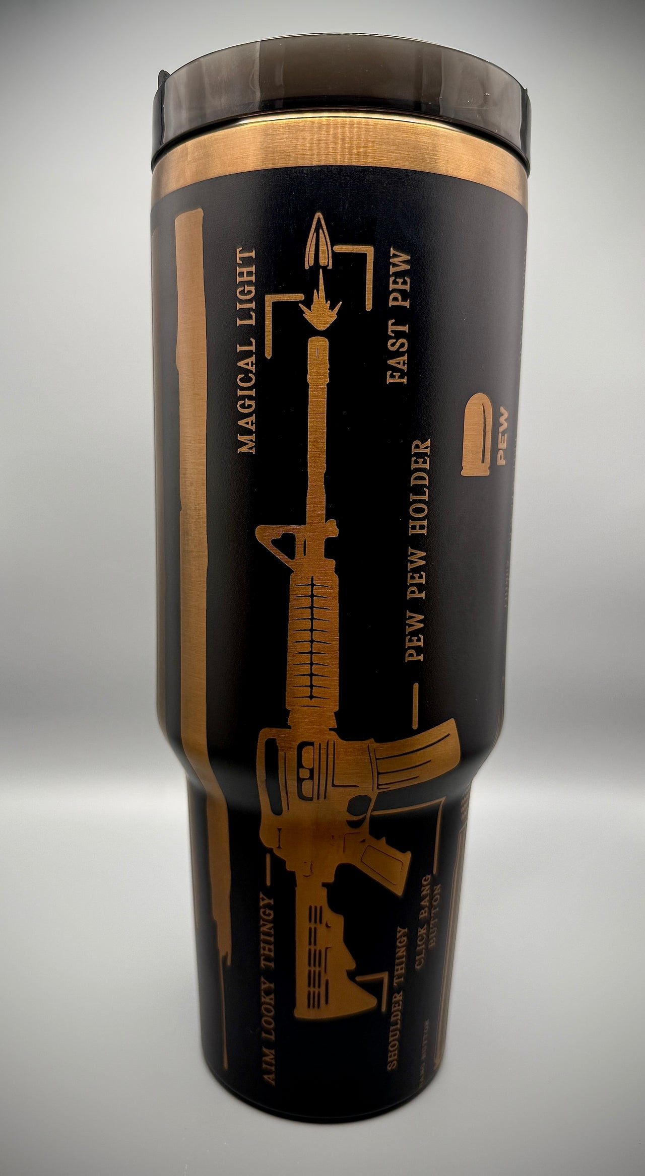 Black tumbler with gold text and graphics on a gray background